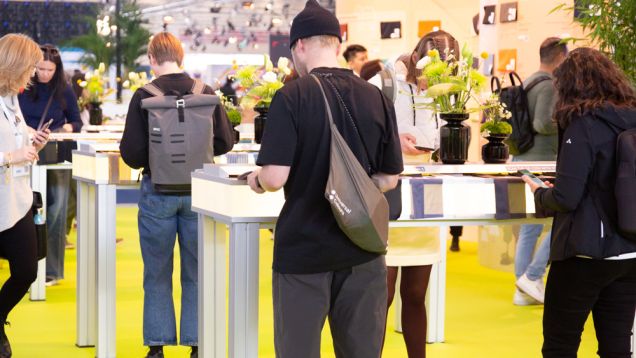 People stand at the PERFORMANCE FORUM at the APril 2023 PERFORMANCE DAYS exhibition and look at the latest trends and innovations in textiles.