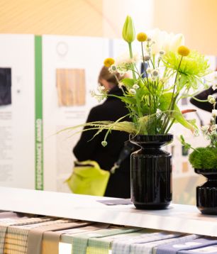 Flowers on a forum table with textile innovations in front of the Focus Topic wall at PERFORMANCE DAYS April 2023
