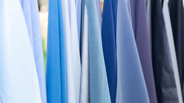 Hanging fabrics in a close-up with colour gradient from light blue to dark blue.